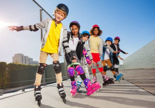 Group of multiethnic boys and girls, in-line skaters, standing one after another outdoors in summer